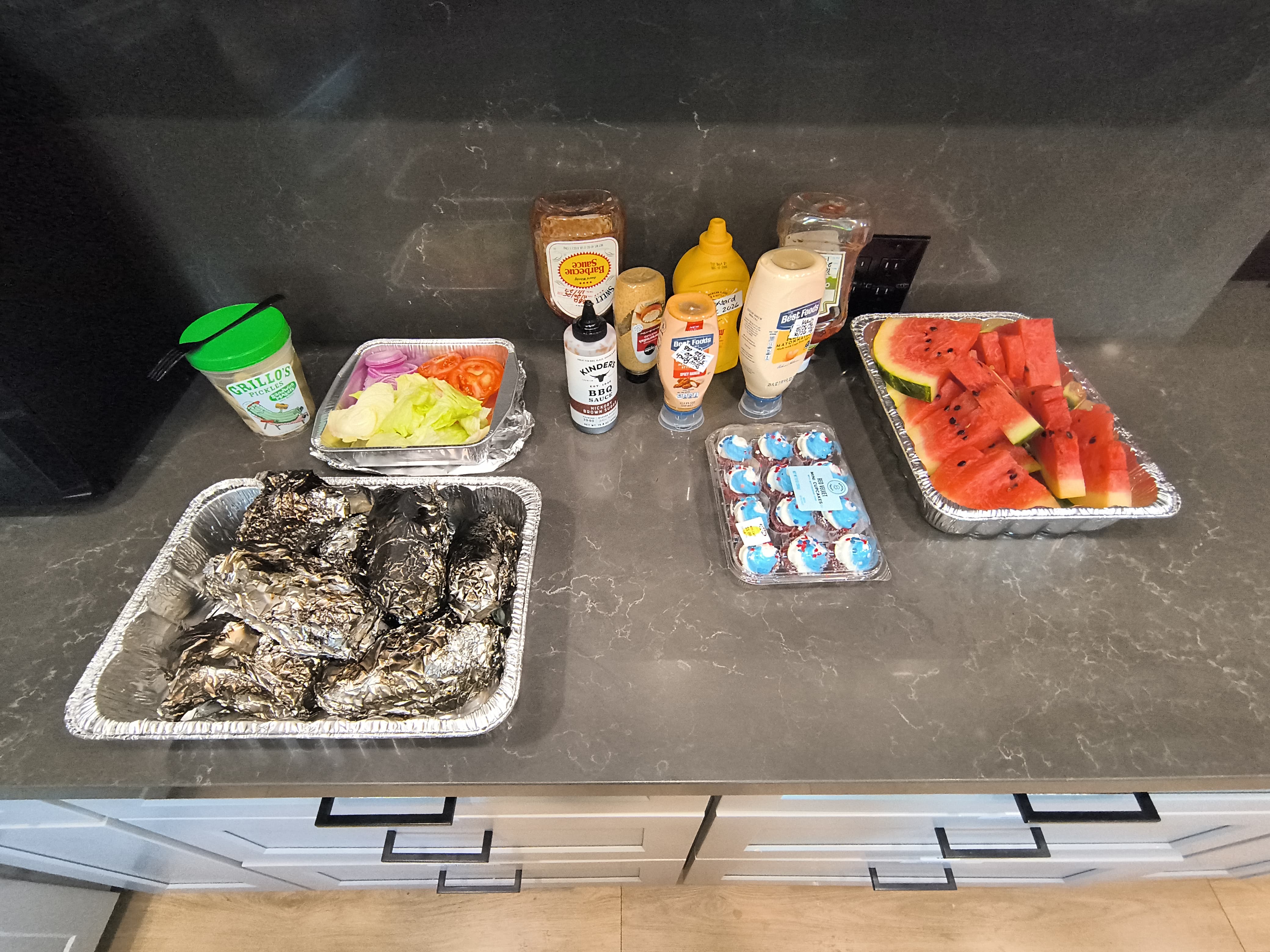 BBQ meal prep with burgers, watermelon, and toppings for a communal gathering
