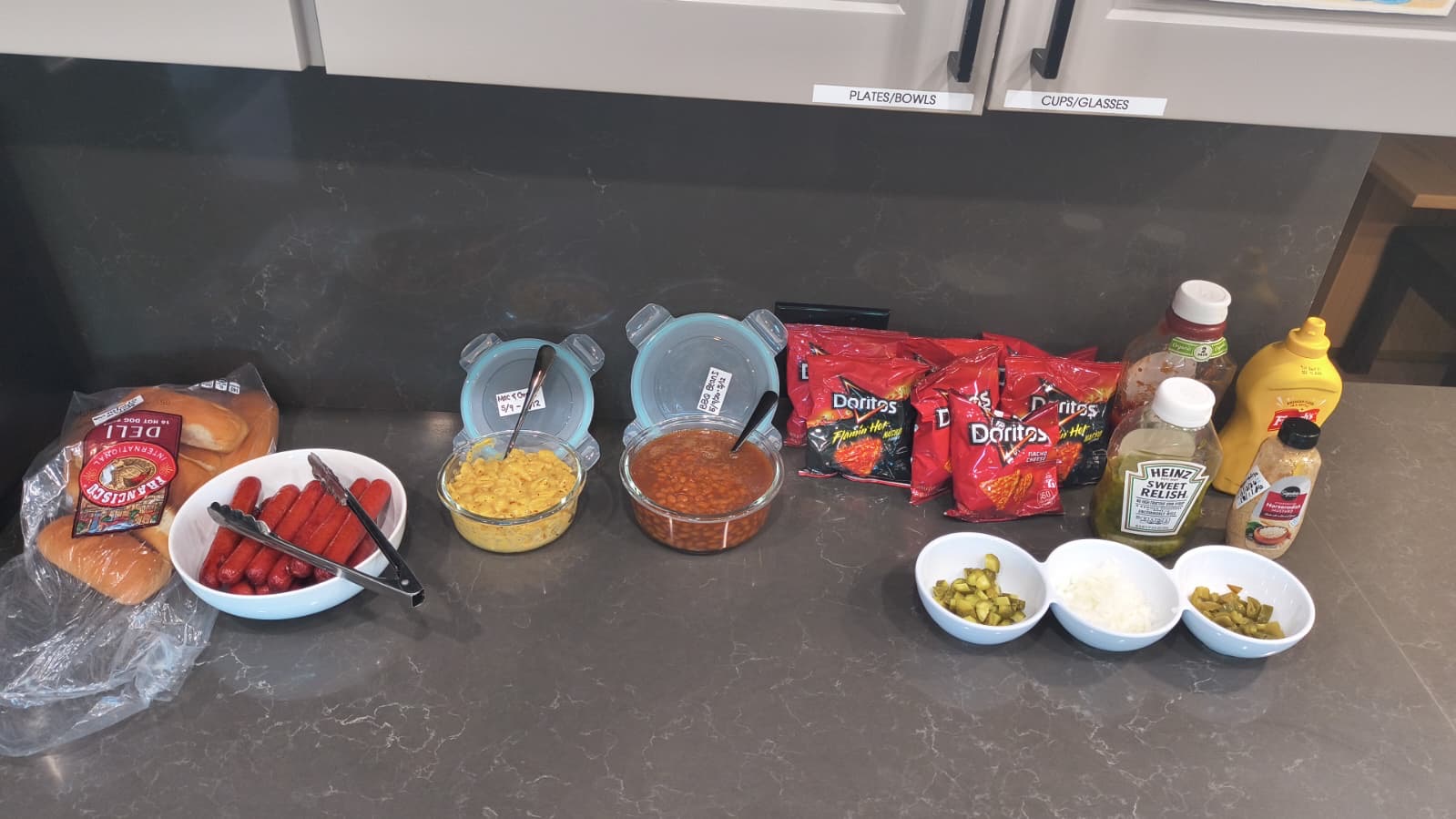 Hot dog cookout spread with toppings and sides for a communal meal